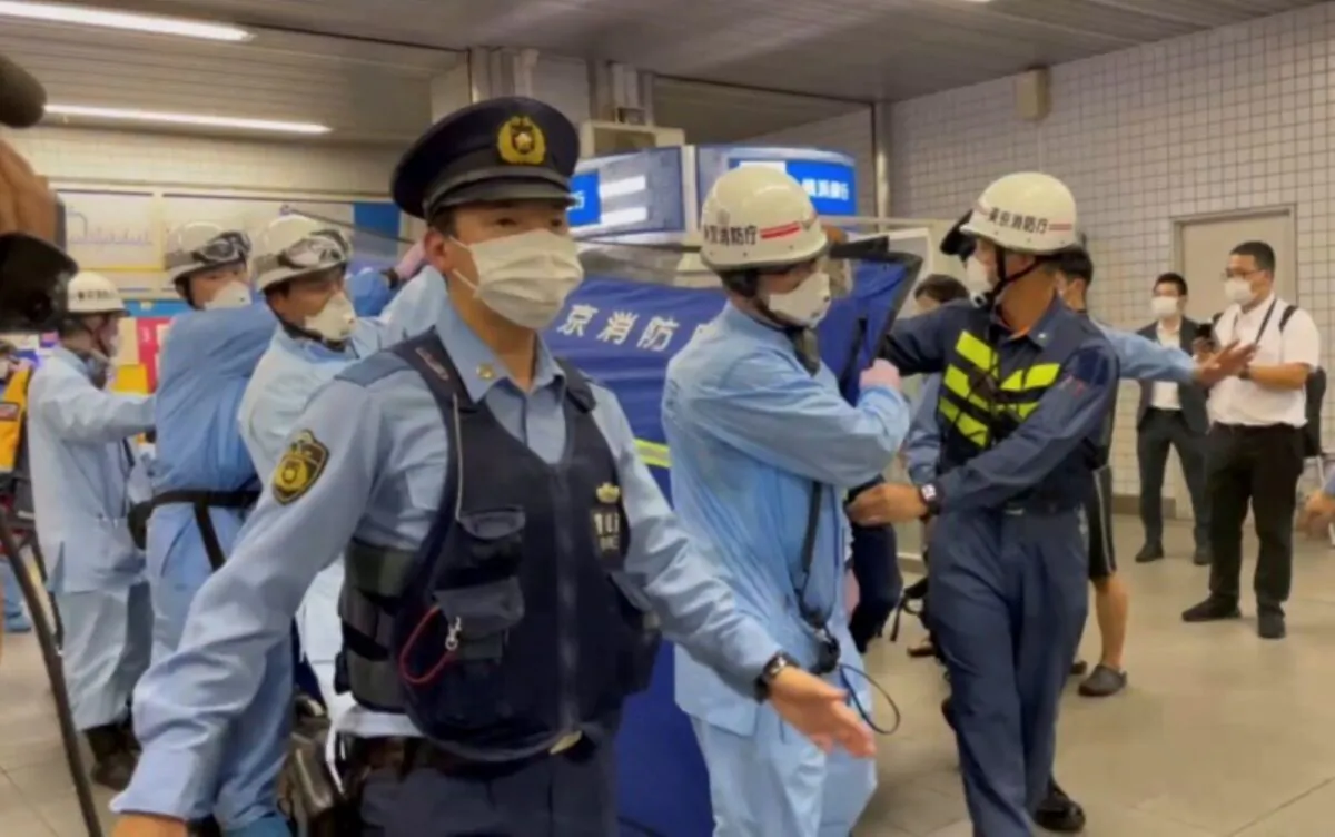 Police escort rescue workers carrying a person through a train station after a knife attack on a train in Tokyo, in this still image taken from video, Japan, on Aug. 6, 2021. (Reuters)