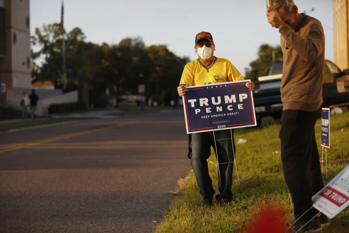 A man posts a Trump-Pence yard sign near the Town 'N Country Regional Public Library in Tampa, Fla., on Nov. 3, 2020. (Octavio Jones/Getty Images)