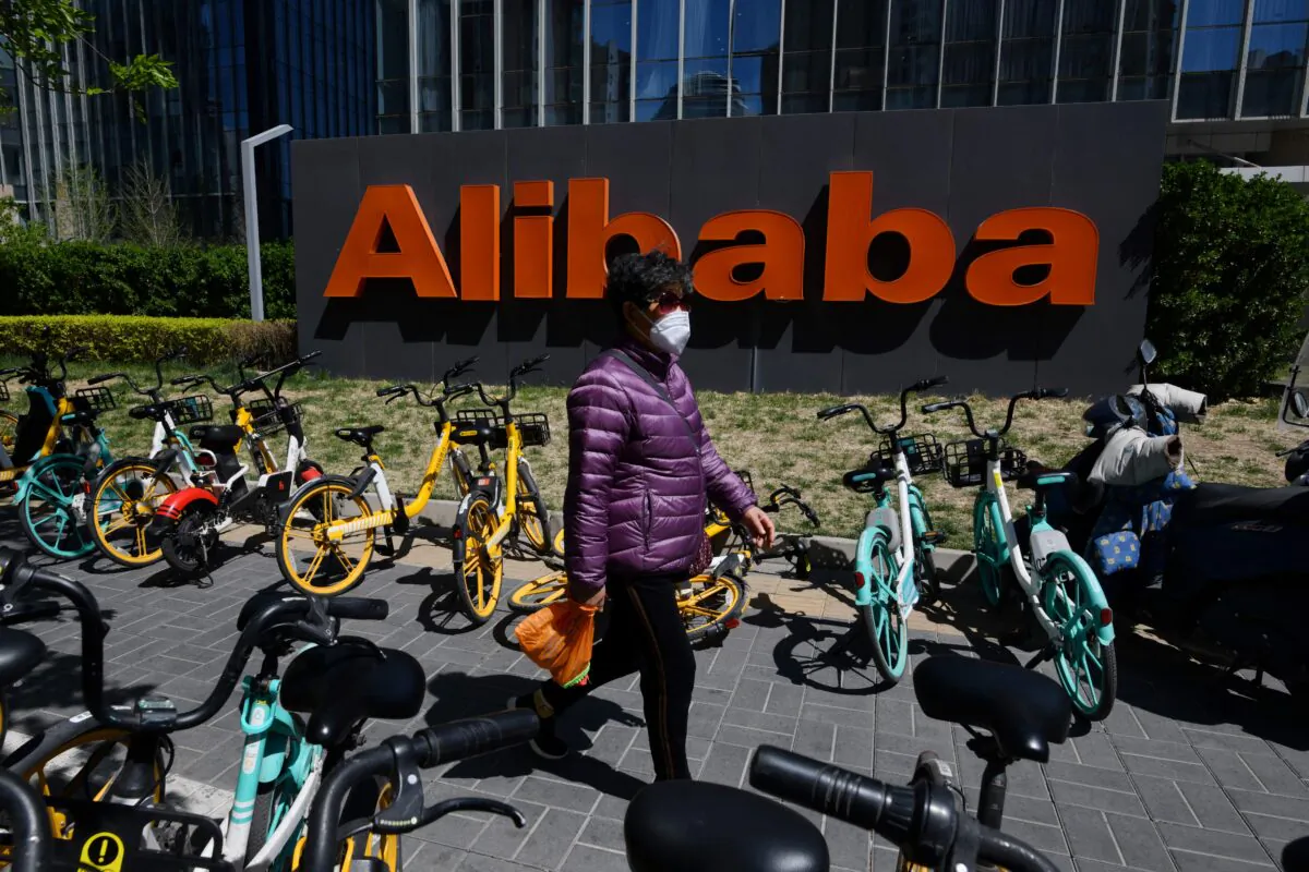 A woman walks past an Alibaba sign outside the company's office in Beijing on April 13, 2021. (Greg Baker/AFP via Getty Images)