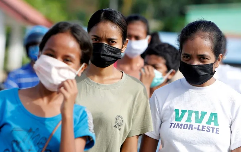 Women wearing protective masks look on as they walk on a street after the government announced new cases of COVID-19 in Dili, East Timor, on April 16, 2020. (Lirio da Fonseca/File Photo/Reuters)