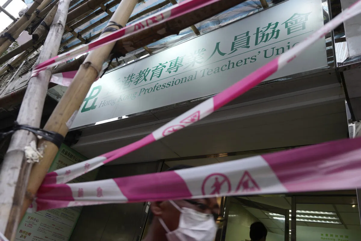 People walk past the entrance of the Hong Kong Professional Teachers' Union in Hong Kong, on Aug. 10, 2021. (Vincent Yu/AP Photo)