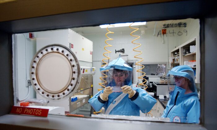 Scientists are working inside the bio-level 4 lab research at the U.S. Army Medical Research Institute of Infectious Diseases at Fort Detrick, Maryland, on Sept. 26, 2002. (Olivier Douliery/AFP via Getty Images)
