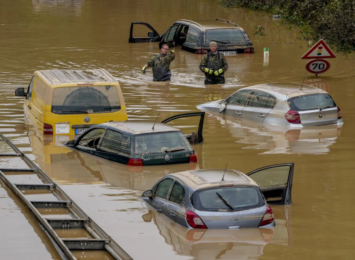 People check for victims in flooded cars on a road in Erftstadt, Germany, on July 17, 2021. (Michael Probst/AP Photo)