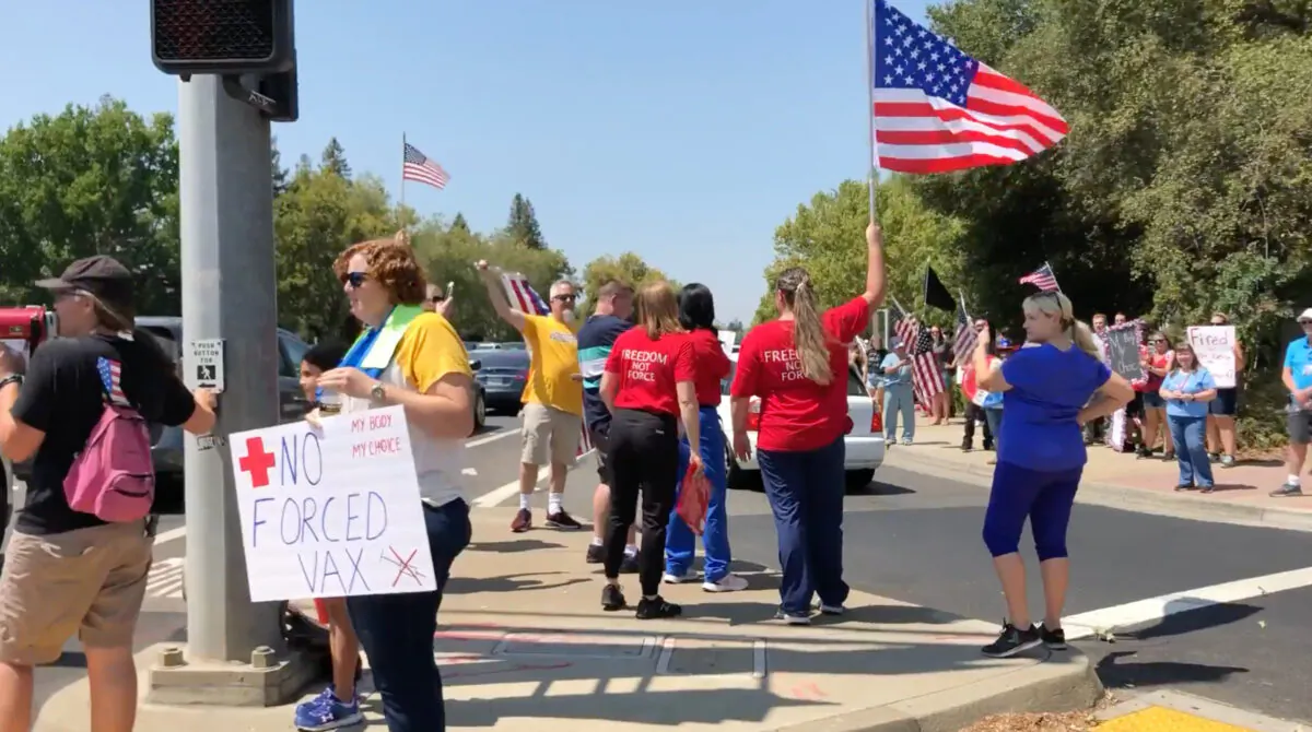Protesters with flags, banners, and signs stand along the sidewalk on Eureka Road in Roseville, Calif., on Aug. 9, 2021. (Courtesy of Rui Ren)