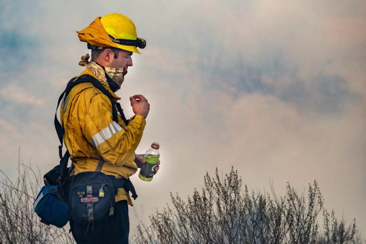 OCFA firefighter takes a sip of Gatorade during the Bond fire on Dec. 5, 2020. (John Fredricks/The Epoch Times)