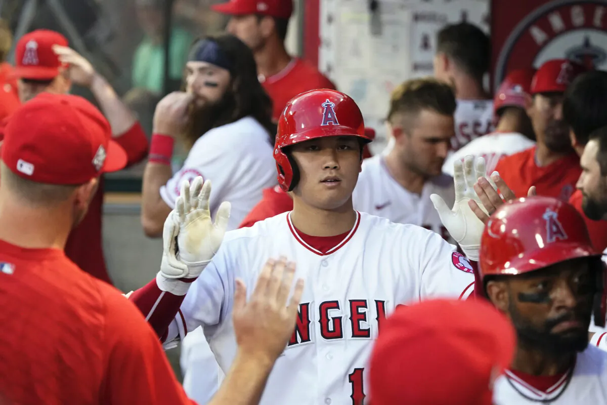 Los Angeles Angels' Shohei Ohtani celebrates his two-run home run with teammates in the dugout during the third inning of a baseball game against the Toronto Blue Jays, in Anaheim, Calif., on Aug. 11, 2021. (AP Photo/Marcio Jose Sanchez)