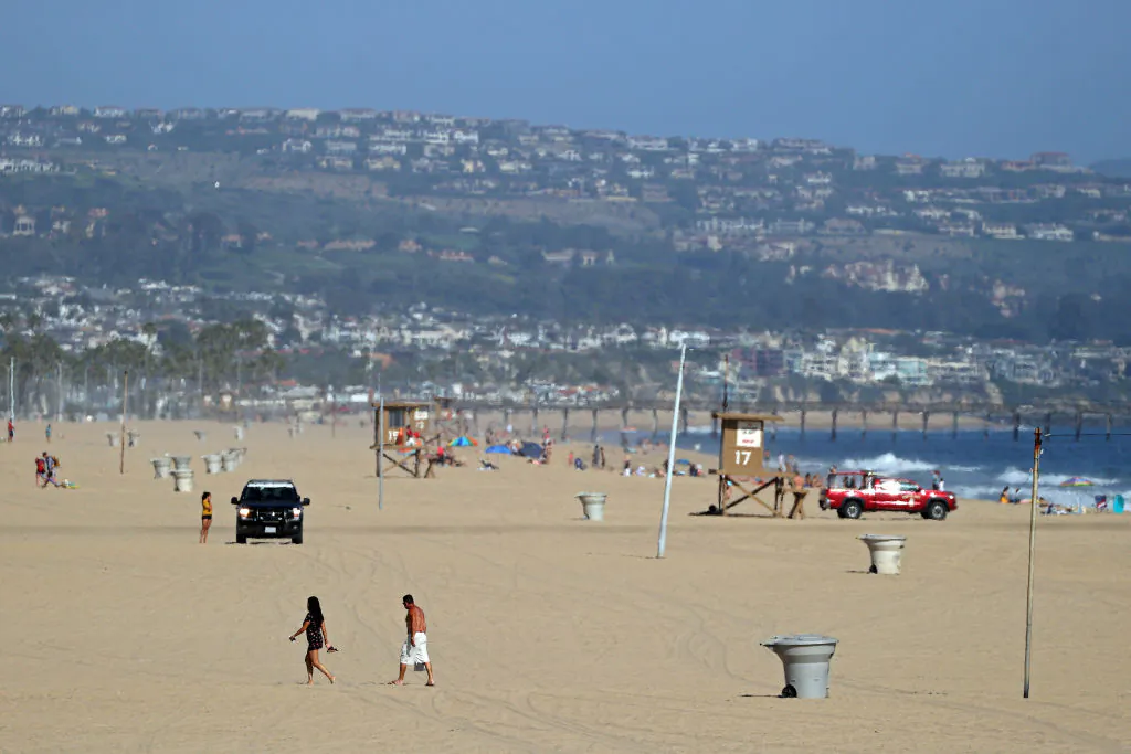 Police and lifeguards patrol as people walk on the beach south of Newport Pier in Newport Beach, Calif., on May 3, 2020. (Michael Heiman/Getty Images)