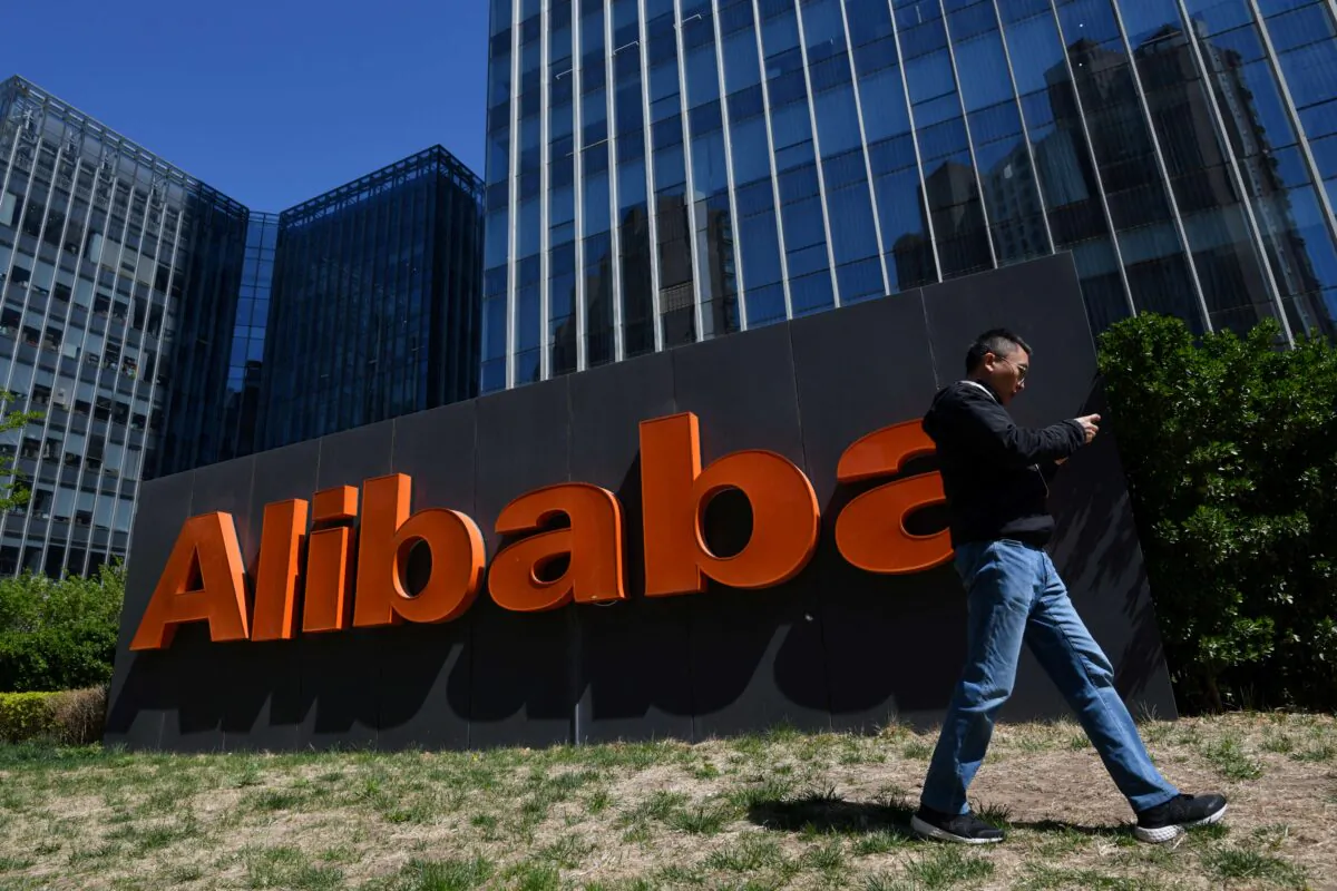 A man walks past an Alibaba sign outside the company's office in Beijing on April 13, 2021. (Greg Baker/AFP via Getty Images)