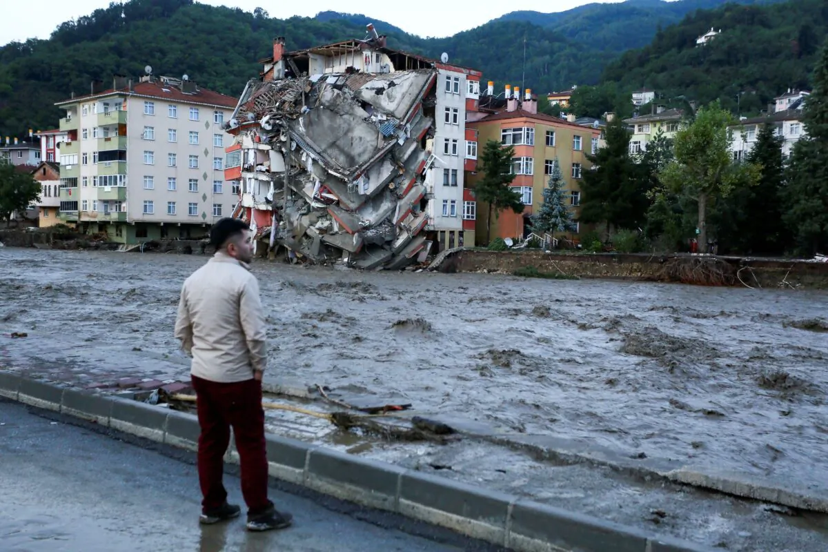 A man looks on as flood waters sweep by in Bozkurt town of Kastamonu province of Turkey, on Aug. 12, 2021. (IHA via AP)
