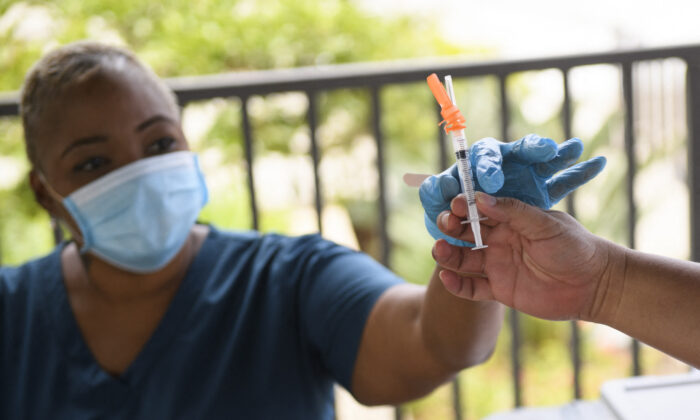 A nurse is handed a dose of the Pfizer COVID-19 vaccine before administering it to a college student during a City of Long Beach Public Health COVID-19 mobile vaccination clinic at the California State University Long Beach (CSULB) campus in Long Beach, Calif., on Aug. 11, 2021 (Patrick T. Fallon/AFP via Getty Images)