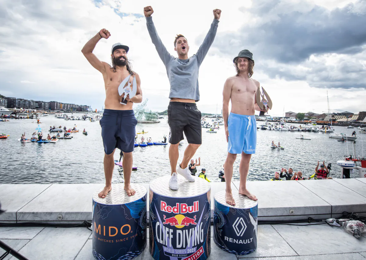 (L–R) Catalin Preda of Romania, Constantin Popovici of Romania, and Gary Hunt of France celebrate on the podium at the Oslo Opera House after the final competition day of the Red Bull Cliff Diving Exhibition in Oslo, Norway, on Aug. 13, 2021. (Romina Amato/Red Bull Content Pool)