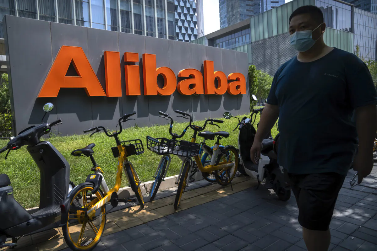 A man wearing a face mask walks past the offices of Chinese e-commerce firm Alibaba in Beijing, on Aug. 10, 2021. (AP Photo/Mark Schiefelbein)
