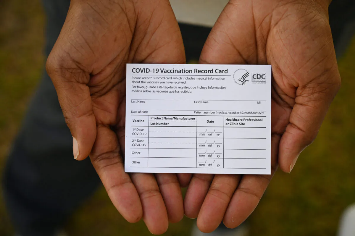 A health care worker displays a COVID-19 Vaccination Record Card during a vaccine and health clinic at QueensCare Health Center in a predominantly Latino neighborhood in Los Angeles, Calif., on Aug. 11, 2021. (Robyn Beck/AFP via Getty Images)