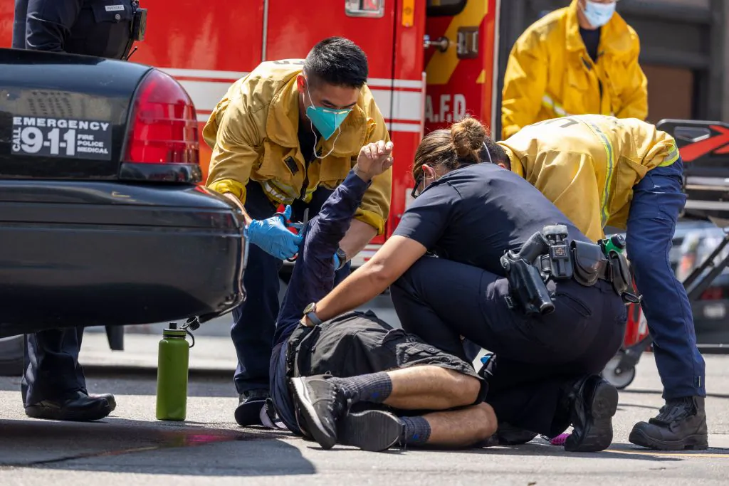 Police and EMTs assist a man who was injured during fights between protesters against vaccine mandates and counter protesters during a rally near City Hall following the Los Angeles City Council vote earlier this week to draw up an ordinance to require proof of vaccination to enter many public indoor spaces, in Los Angeles on August 14, 2021. (David McNew/AFP via Getty Images)
