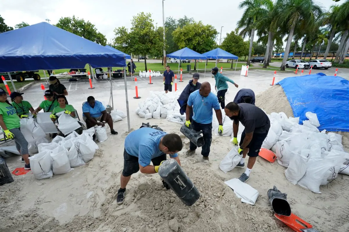City workers fill sandbags at a drive-thru sandbag distribution event for residents ahead of the arrival of rains associated with tropical depression Fred, at Grapeland Park in Miami, Fla., on Aug. 13, 2021. (Wilfredo Lee/AP Photo)