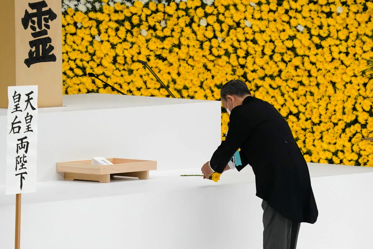 Japanese Prime Minister Yoshihide Suga lays a flower during a memorial service marking the 76th anniversary of the end of World War II in Tokyo, Japan, on Aug. 15, 2021. (Toru Hanai/Pool via Reuters)