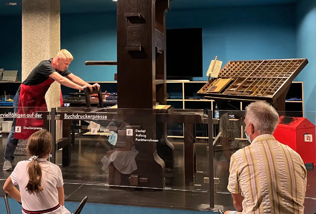 A docent in Mainz demonstrates to international visitors how the original Gutenberg printing press would have worked. (Lesley Sauls Frederikson)