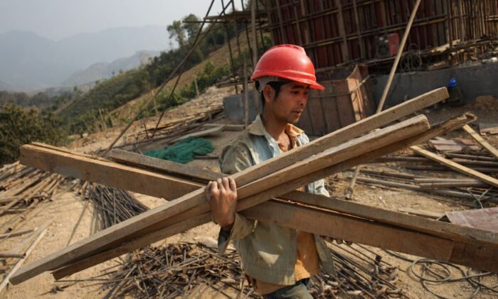 A Chinese worker carries materials for the first rail line linking China to Laos, a key part of Beijing's "Belt and Road" project across the Mekong in Luang Prabang, Laos, on Feb. 8, 2020. (Aidan Jones/AFP via Getty Images)