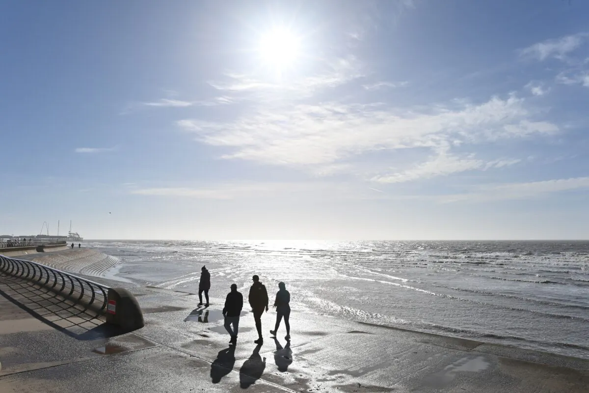 People enjoy the sunshine as they walk along the beach in Blackpool, Lancashire, United Kingdom on March 16, 2021. (Paul Ellis/AFP via Getty Images)