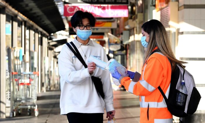 A volunteer distributes face masks in Bankstown suburb of Sydney, Australia, on Aug. 11, 2021. (Saeed Khan/AFP via Getty Images)