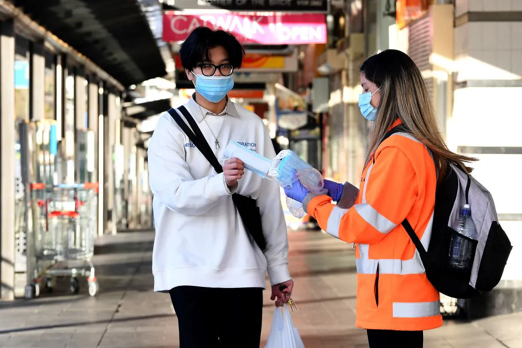 A volunteer distributes face masks in Bankstown suburb of Sydney, Australia, on Aug. 11, 2021. (Saeed Khan/AFP via Getty Images)
