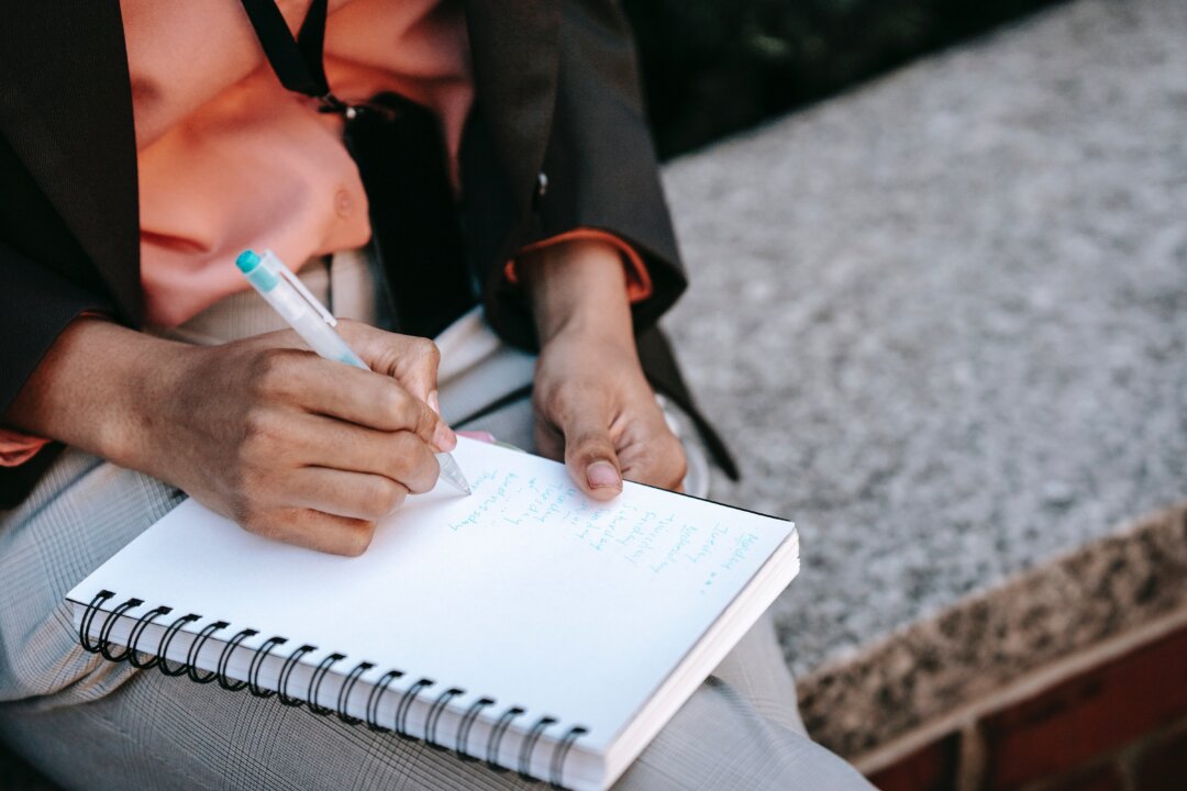 A person writing on a notepad. (Ono Kosuki/Pexels)