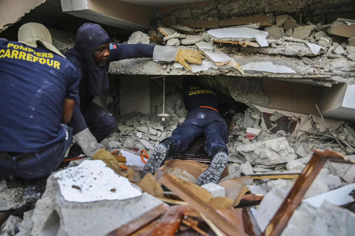 Firefighters search for survivors inside a collapsed building, after the Aug. 14 7.2 magnitude earthquake in Les Cayes, Haiti, Sunday, Aug. 15, 2021. (AP Photo/Joseph Odelyn)