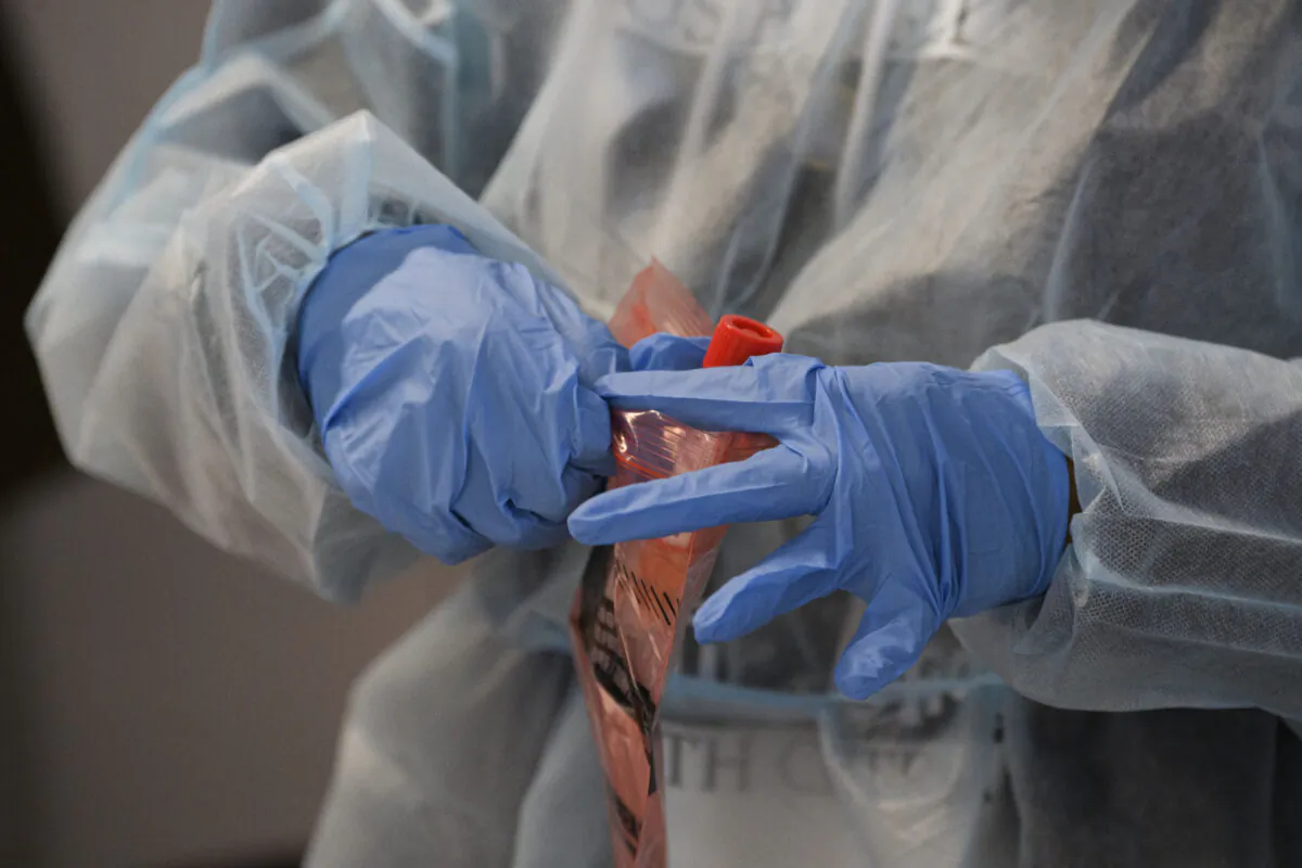 A healthcare worker places a COVID-19 nasal swab test for a traveler to Hawaii into a specimen bag during the Covid-19 pandemic at Los Angeles International Airport (LAX) in Los Angeles, Calif., on Nov. 18, 2020. (Patrick Fallon/AFP via Getty Images)