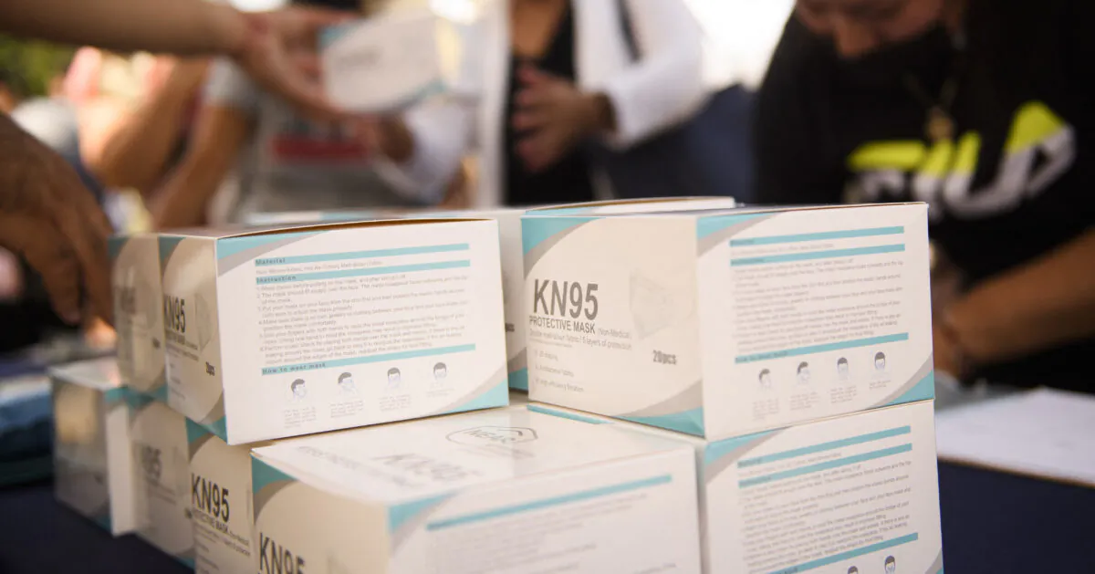 People receive boxes of KN95 face masks during a back-to-school event offering school supplies, COVID-19 vaccinations, face masks, and other resources for children and their families at the Weingart East Los Angeles YMCA in Los Angeles, California, on Aug. 7, 2021. (Patrick T. Fallon/AFP via Getty Images)