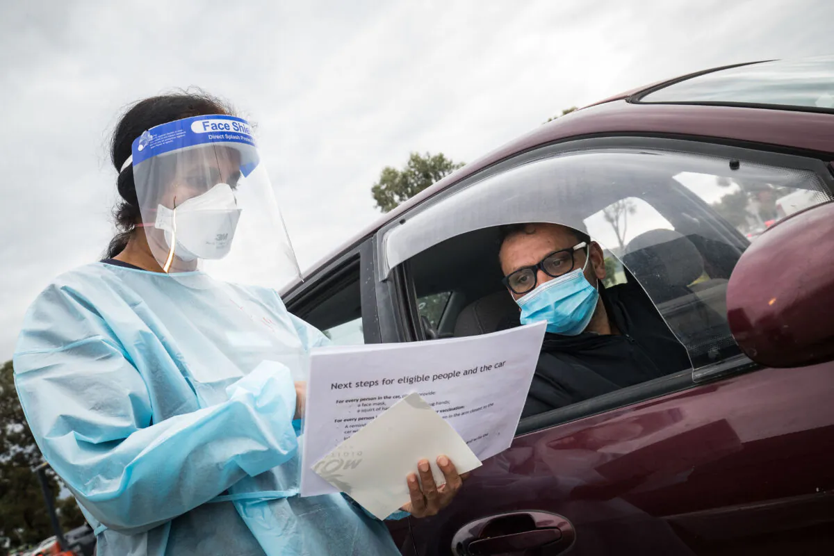 A nurse takes a man's information before administering the Pfizer COVID-19 vaccine at a drive through vaccination centre in Melton, Melbourne, Victoria on Aug. 09, 2021. (Photo by Darrian Traynor/Getty Images)