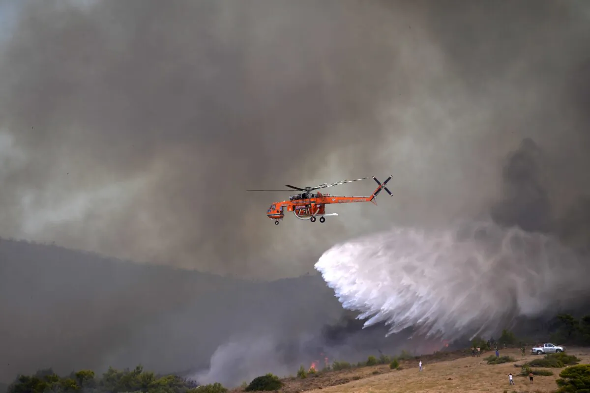 An helicopter drops water over a fire in Siderina village helicopter about 55 kilometers (34 miles) south of Athens, Greece, on Aug. 16, 2021. (Thanassis Stavrakis/AP Photo)