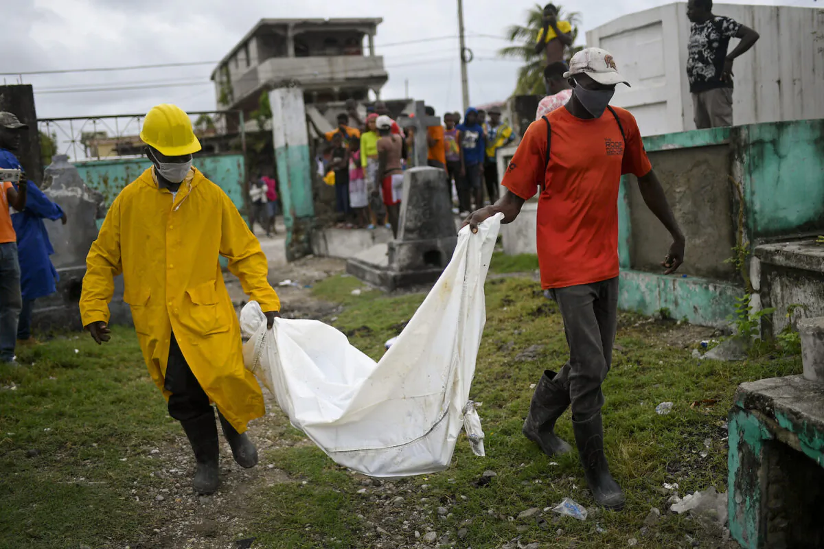 Men carry the body of a boy that was found in collapsed building lies at the back of a truck at the entrance of the cemetery in Les Cayes, Haiti, on Aug. 17, 2021. (Matias Delacroix/AP Photo)