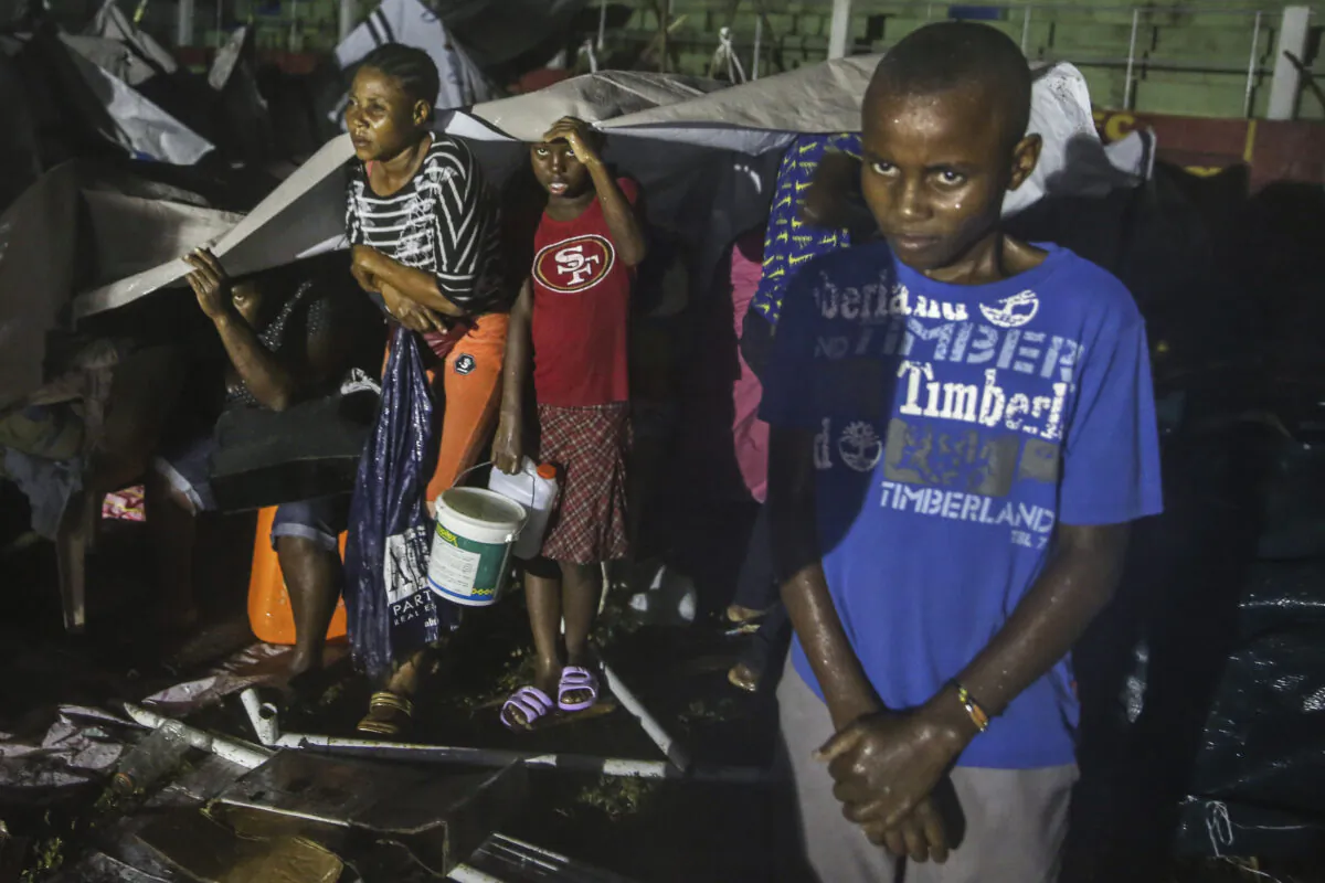 People affected by the Saturday's earthquake take cover from the rain of Tropical Depression Grace at a refugee camp in Les Cayes, Haiti, on Aug. 16, 2021. (Joseph Odelyn/AP Photo)