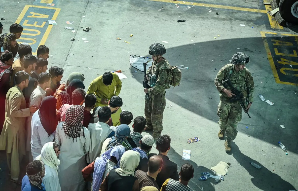 US soldiers stand guard as Afghan people wait at the Kabul airport in Kabul, Afghanistan on Aug. 16, 2021. (Wakil Kohsar/AFP via Getty Images)