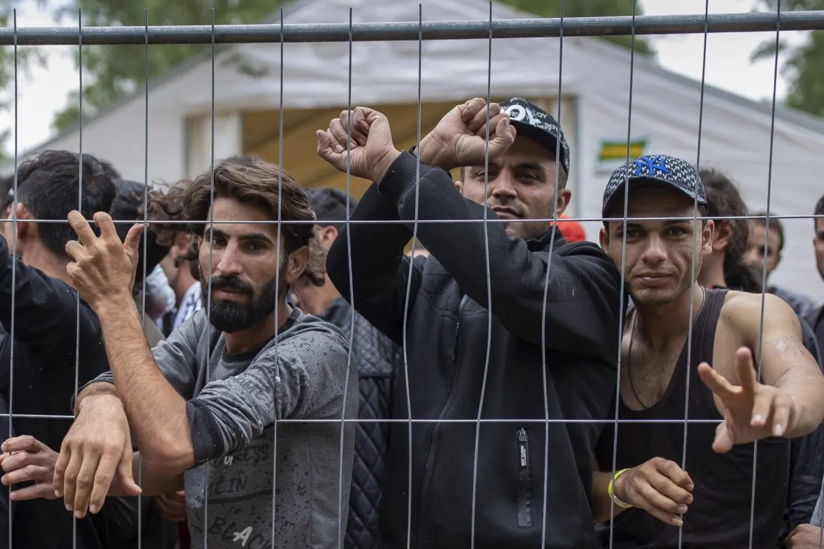 Illegal immigrants stand behind a fence inside the newly built refugee camp in the Rudninkai military training ground, some 38 kilometers (23.6 miles) south from Vilnius, Lithuania, on Aug. 4, 2021. (Mindaugas Kulbis/AP Photo)