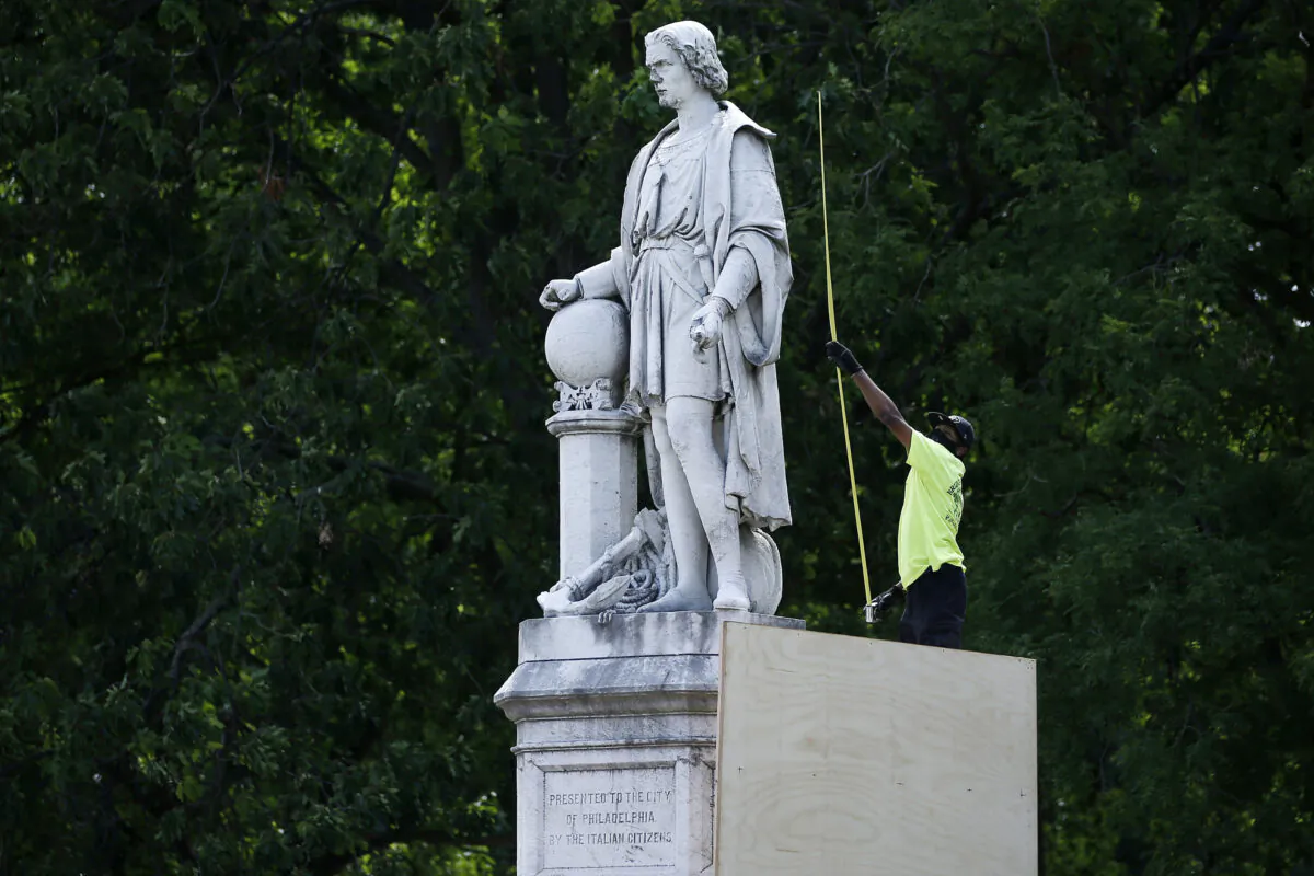 A city worker measures the statue of Christopher Columbus at Marconi Plaza as they build a cover in the South Philadelphia neighborhood of Philadelphia, Pa., on June 16, 2020. (Matt Slocum/AP Photo)