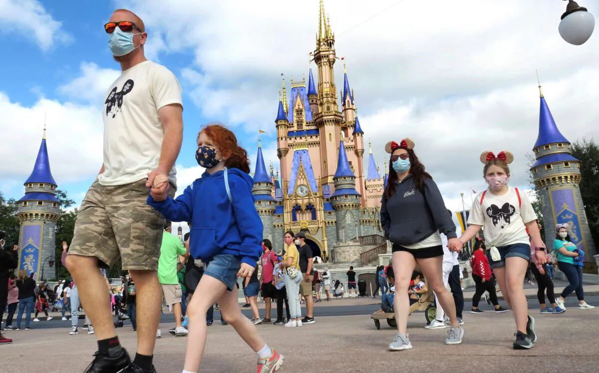 A family walks past Cinderella Castle at Walt Disney World in Lake Buena Vista, Fla., on Dec. 21, 2020. (Joe Burbank/Orlando Sentinel via AP)