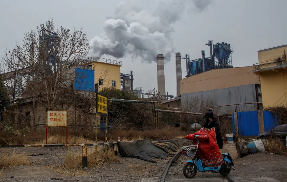 A woman rides a scooter past a steel plant in Anyang, Henan province, China, on Feb. 18, 2019. (Thomas Peter/Reuters)