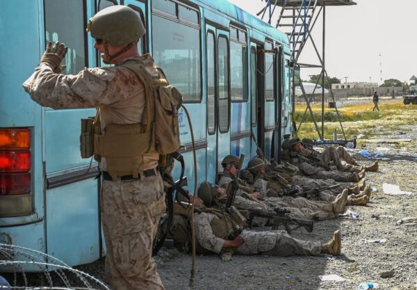 U.S. soldiers rest as Afghan people wait to leave