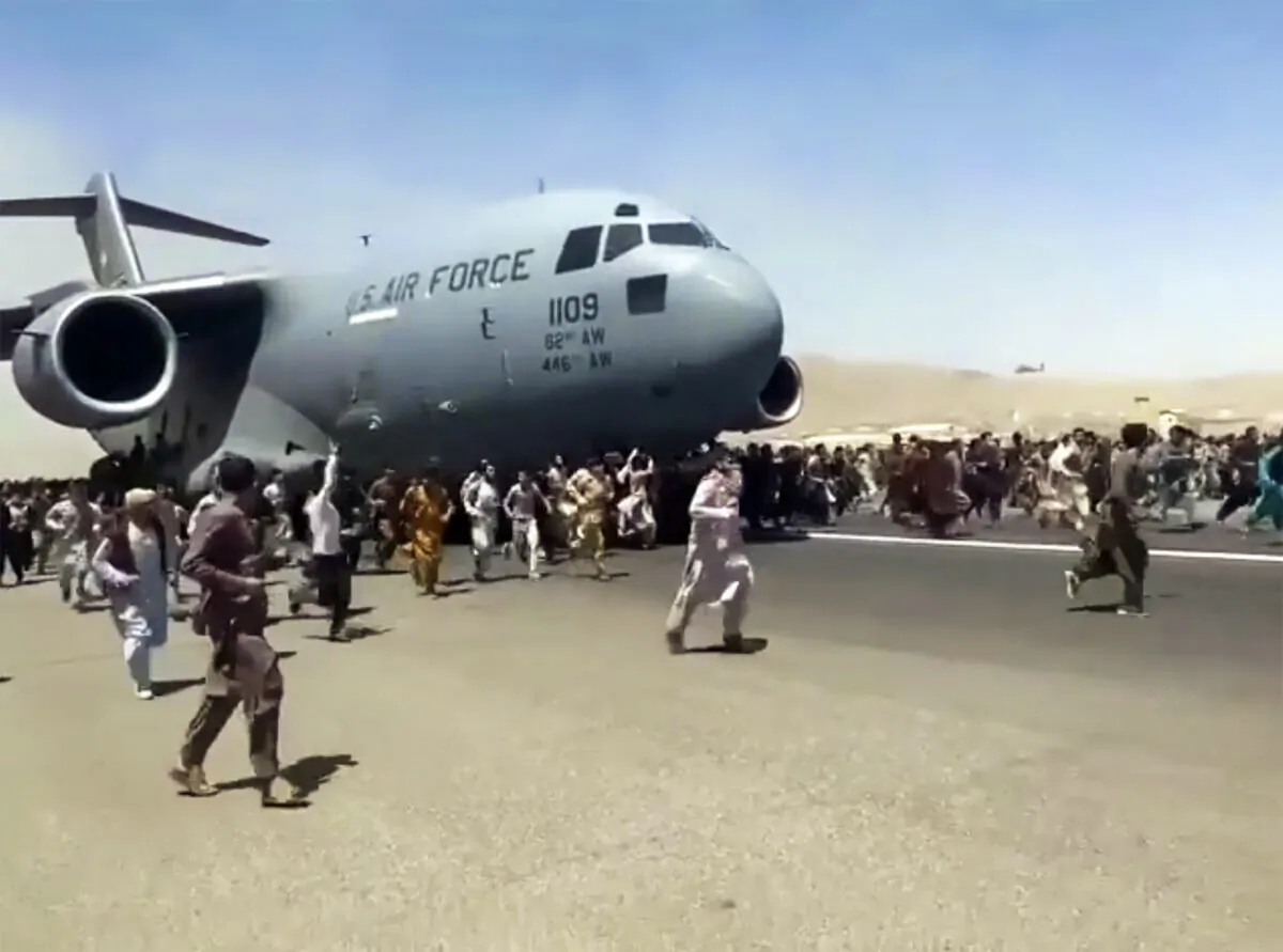 Hundreds of people run alongside a U.S. Air Force C-17 transport plane as it moves down a runway of the international airport, in Kabul, Afghanistan, on Aug. 16. 2021. (Verified UGC via AP)