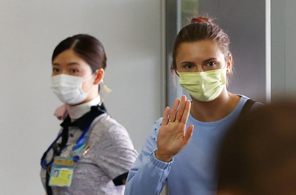 Belarusian Sprinter Krystsina Tsimanouskaya who took refuge in the Polish embassy in Tokyo, waves as she boards a flight to Vienna at Narita International Airport in Narita, east of Tokyo, Japan, on Aug. 4, 2021. (Issei Kato/Reuters)