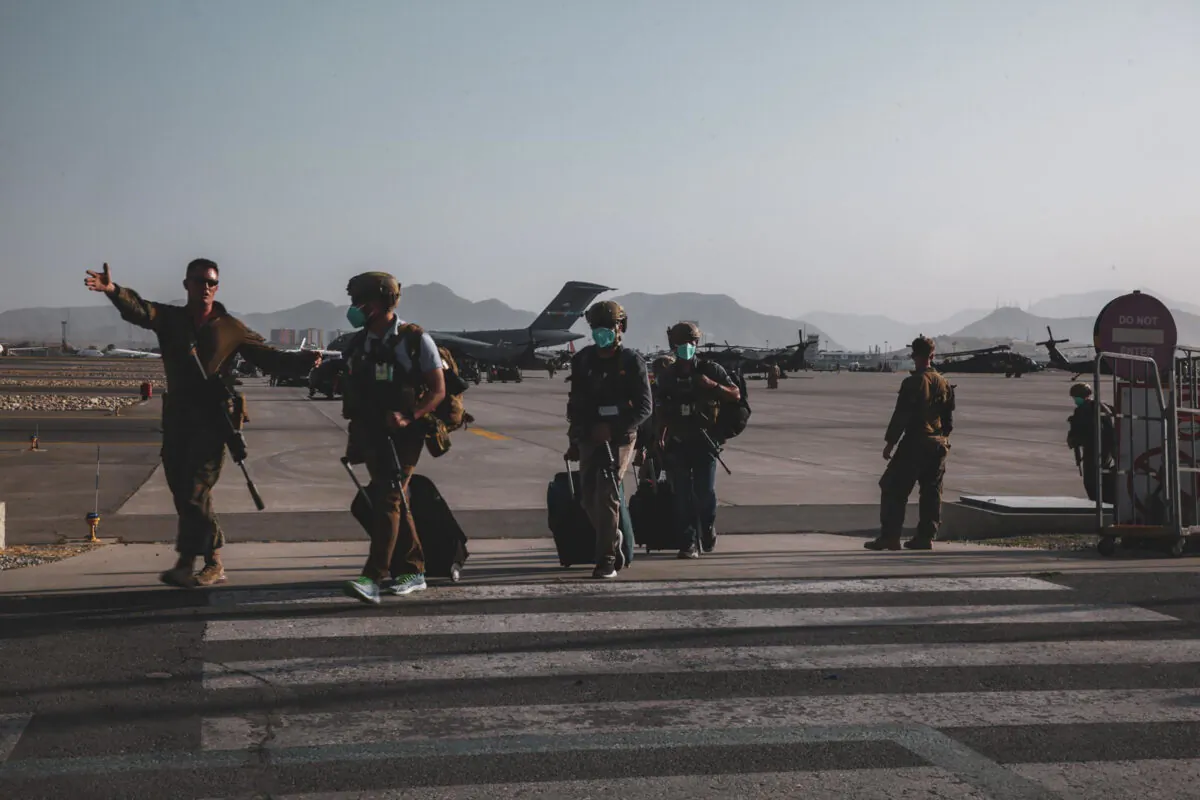 A Marine assigned to the 24th Marine Expeditionary Unit escorts Department of State personnel to be processed for evacuation at Hamid Karzai International Airport, in Kabul, Afghanistan on Aug. 15, 2021. (Sgt. Isaiah Campbell/U.S. Marine Corps via AP)