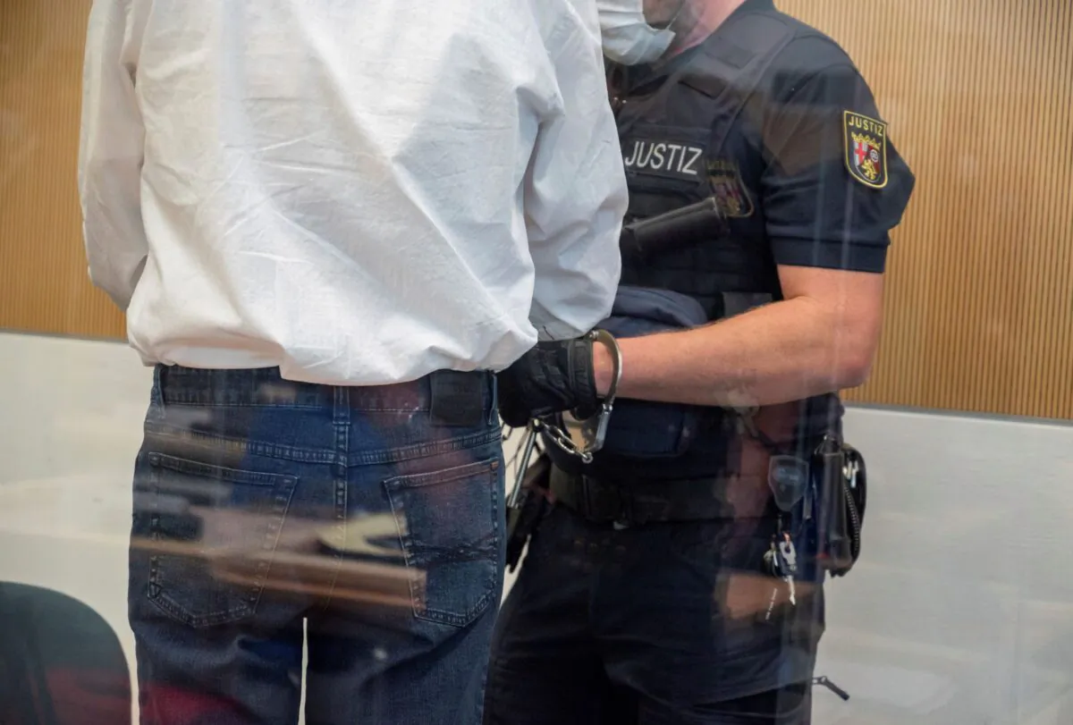 A court official checks the handcuffs of the defendant in a courtroom in Trier, Germany, on Aug. 19, 2021. (Harald Tittel/dpa via AP)
