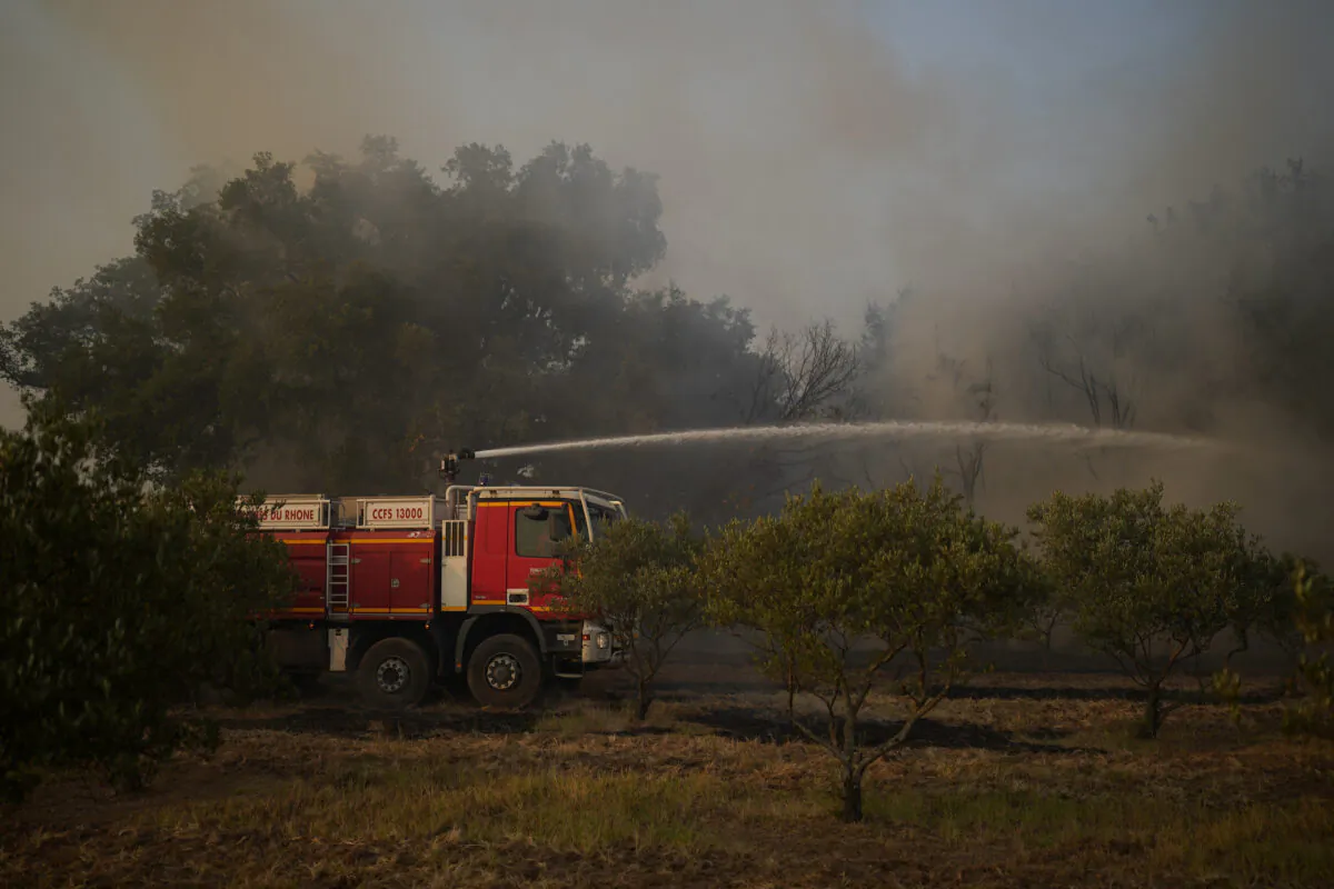 A fire brigade truck hoses a fire next to save olive trees near Le Luc, southern France, on Aug. 18, 2021. (Daniel Cole/AP Photo)