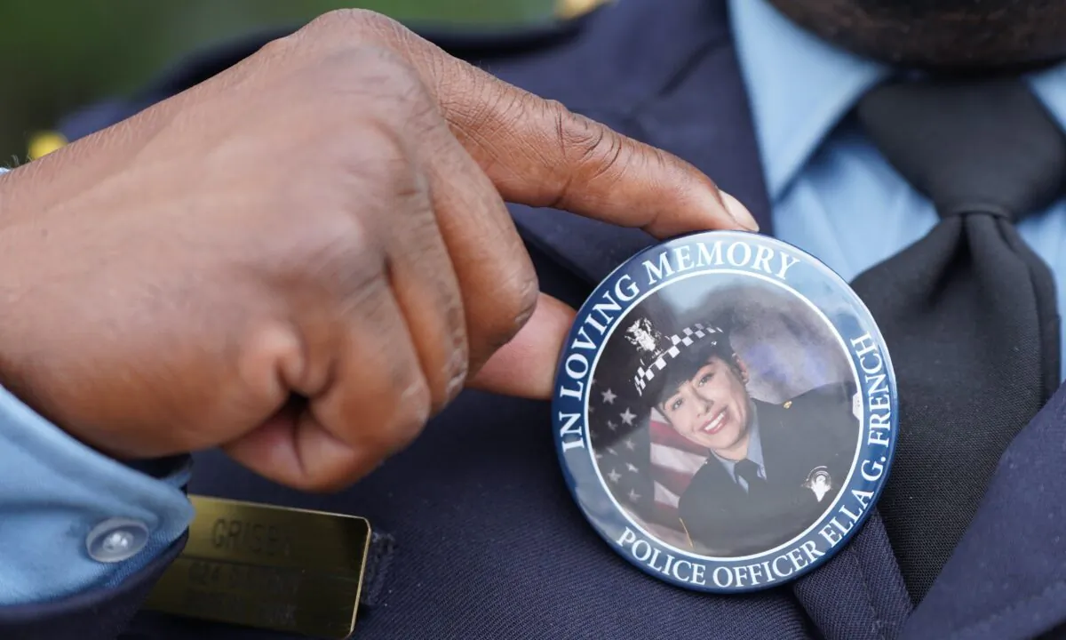 Chicago police officer Timothy Grisby holds up a pin button bearing the image of slain officer Ella French outside St. Rita of Cascia Church in Chicago, IL on Aug. 19, 2021. (Cara Ding/The Epoch Times)