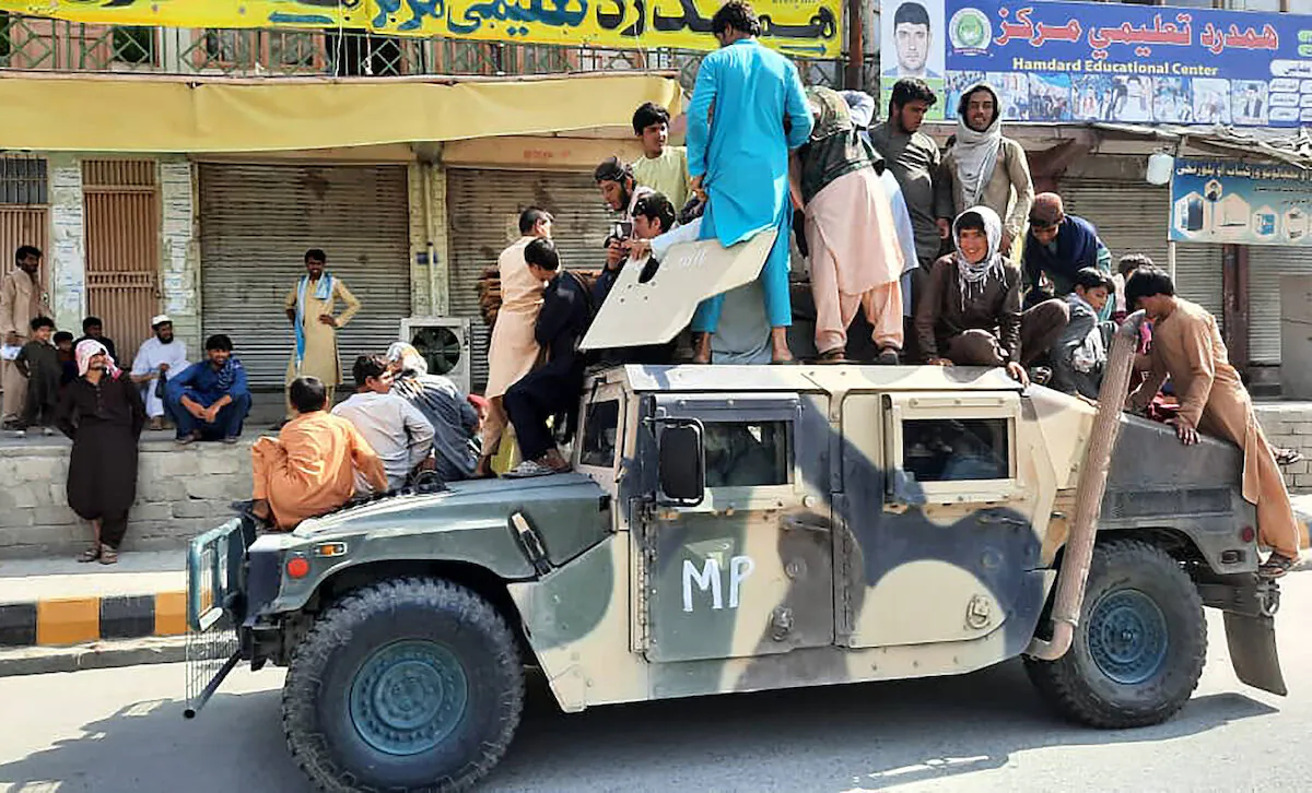 Taliban fighters and local residents sit on an U.S. provided Afghan National Army Humvee vehicle along the roadside in Laghman province on Aug. 15, 2021. (AFP via Getty Images)