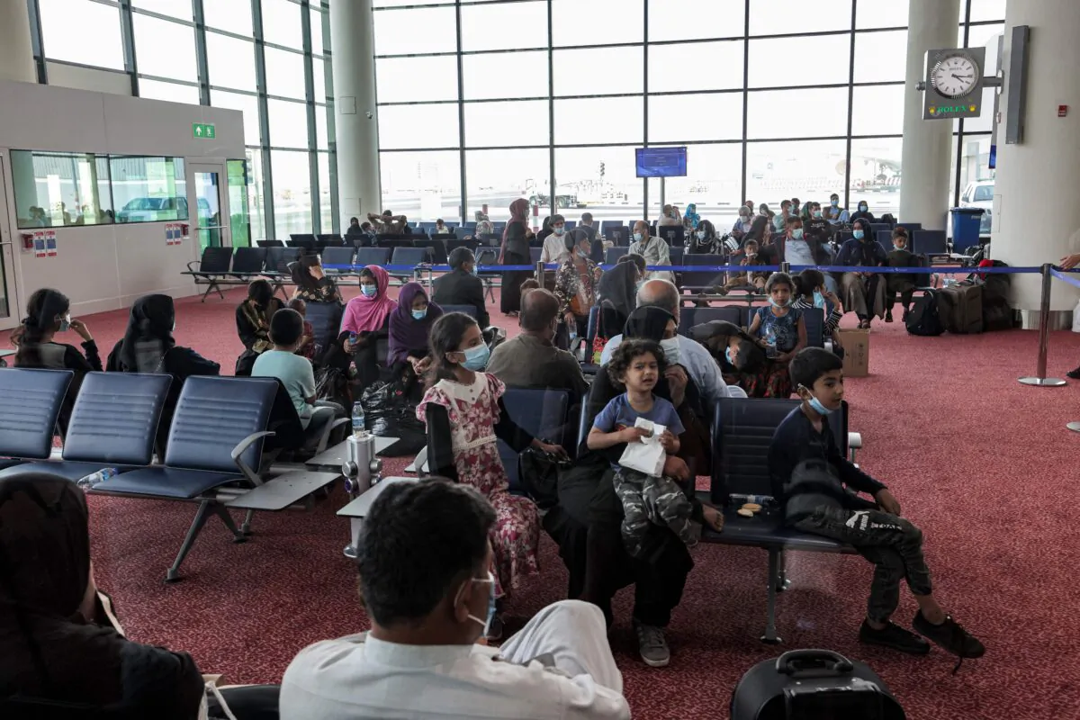 Evacuees from Afghanistan sit in a hall upon their arrival at Al Maktoum International Airport in the United Arab Emirates, on Aug. 19, 2021. (Giuseppe Cacace/AFP via Getty Images)