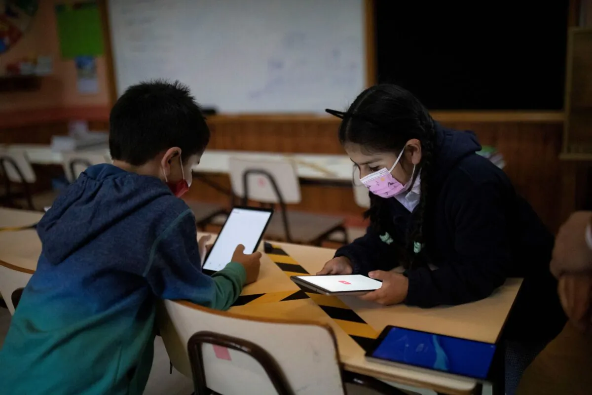 Diego Guerrero, 7, and Sofia Diaz, 7, connect to the internet thanks to Starlink's satellite antenna at the John F Kennedy School, in the village of Sotomo, outside the town of Cochamo, Los Lagos region, Chile, on Aug. 6, 2021. (Pablo Sanhueza/Reuters)
