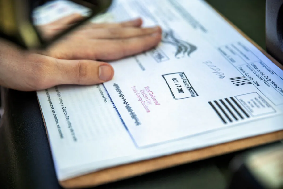 A poll worker stamps a voters ballot before dropping it into a secure box at a ballot drop off location in Texas on Oct. 13, 2020. (Sergio Flores/Getty Images)