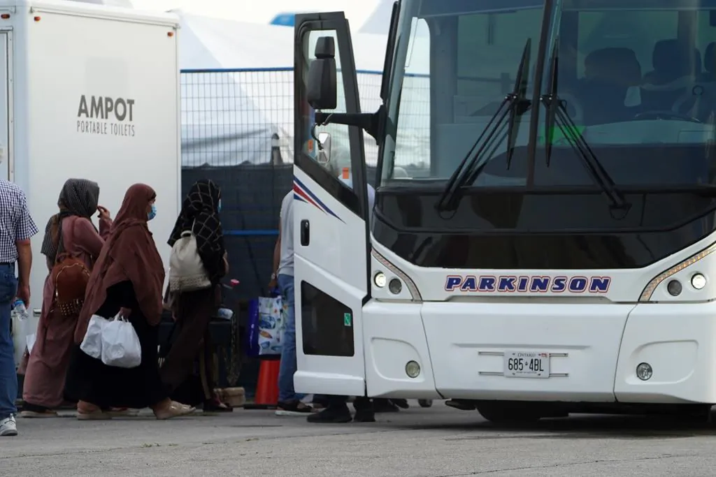 Refugees from Afghanistan and Canadian Citizens board a bus after being processed at Pearson Airport in Toronto, on Aug 17, 2021, after arriving indirectly from Afghanistan. (The Canadian Press/Sean Kilpatrick)